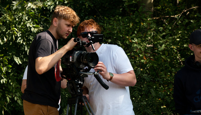 Två killar som filmar med en filmkamera.